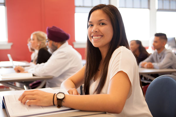 Promotional photo of a student seated in a classroom at Spartanburg Community College. The image shows students engaged in classroom instruction with notebooks and course materials, highlighting academic learning, student engagement, and the college experience.