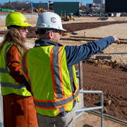 Image of two people with construction vests and hard hats looking at site