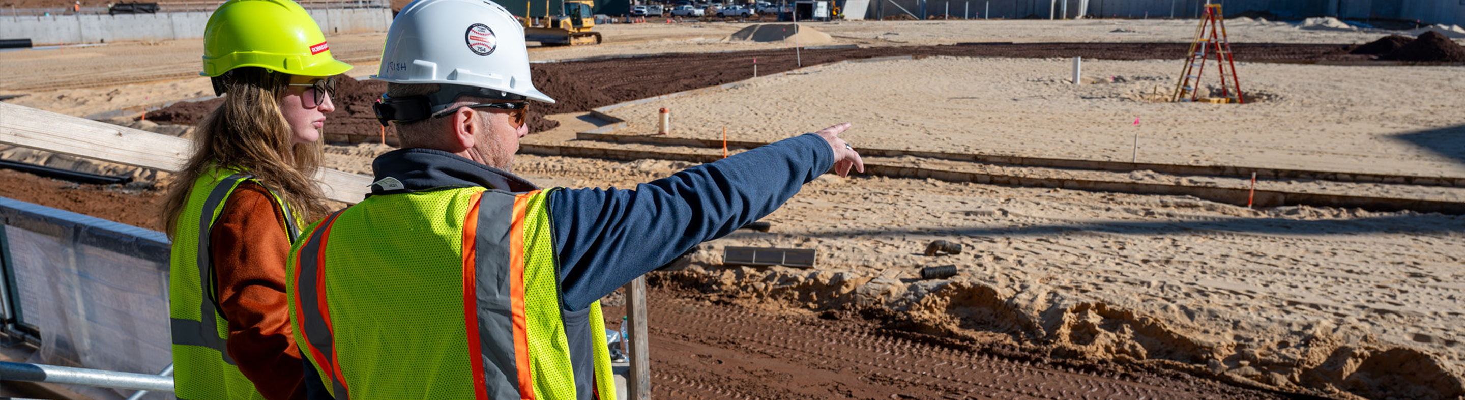 Image of two people in construction vests and hard hats