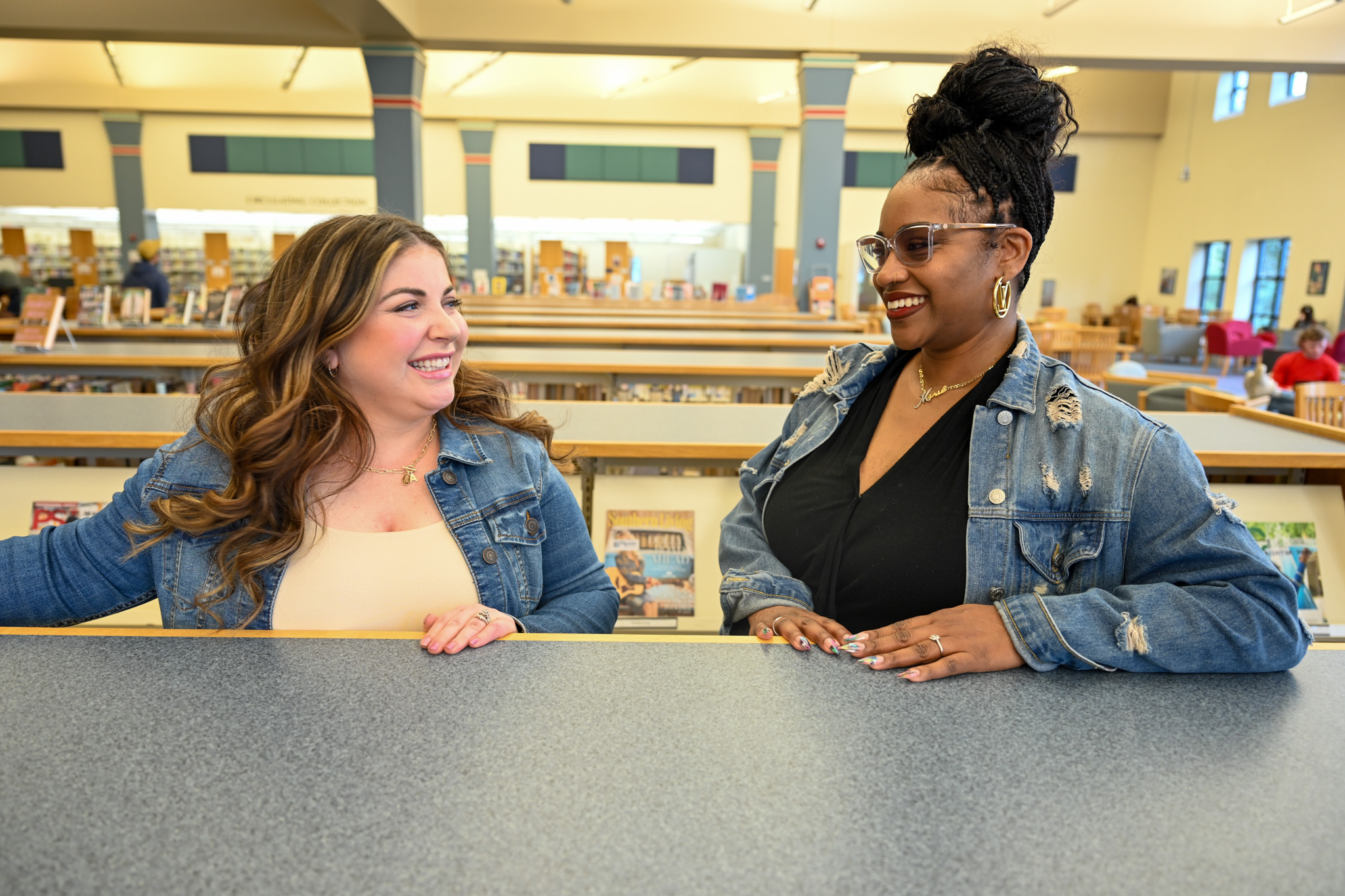 Two people from SCC speak to each other in the library.