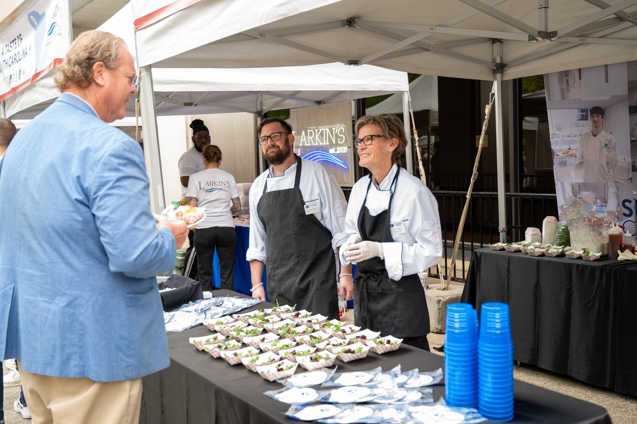 Image of Two Culinary Instructors as they present their dish to a patron.