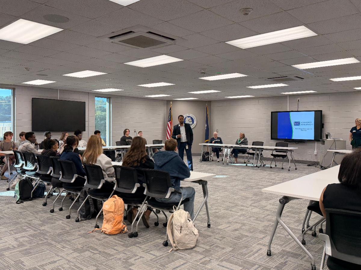 Students gather for a Spartanburg Community College (SCC) Workforce Development seminar. A speaker presents career readiness and technical training opportunities in a collaborative classroom setting.