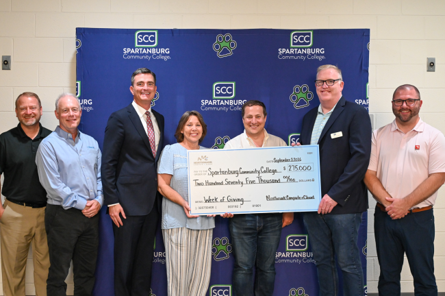 Spartanburg Community College check presentation flyer. Four smiling people holding a large donation check for $275,000 from Northmark Compute + Cloud for the Week of Giving, dated September 3, 2026
