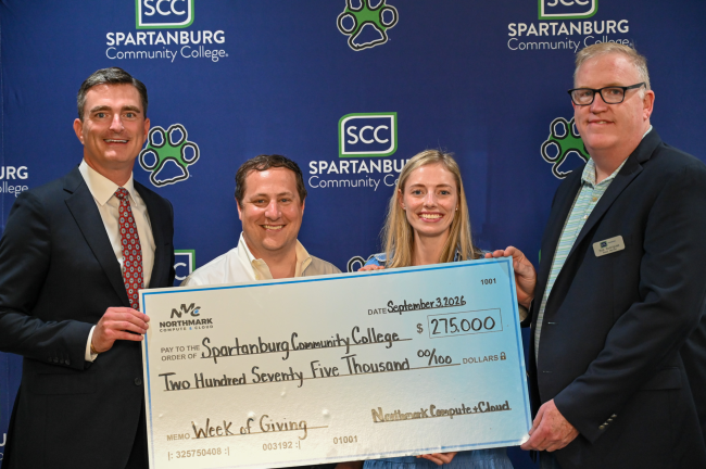 Spartanburg Community College check presentation flyer. Four smiling people holding a large donation check for $275,000 from Northmark Compute + Cloud for the Week of Giving, dated September 3, 2026.